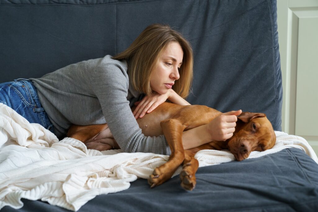 Upset woman care of weakening old dog at home. Needing end of life care for pets